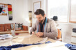 © Pixel-Shot - Male tailor making pattern at table in atelier