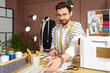 © Pixel-Shot - Male tailor with fabric samples at table in atelier