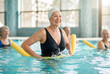© Meow Creations - Happy senior woman doing aqua aerobics with foam noodle in pool