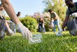 © Meow Creations - Group of diverse volunteers cleaning green park grass and picking up plastic waste