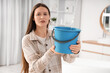 © Pixel-Shot - Upset young woman placing blue bucket under water dripping from ceiling in bathroom