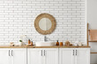 © Pixel-Shot - Sink, bath supplies on chest of drawers, mirror and shelves on white brick wall in bathroom
