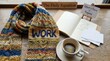 © Faiz - Cozy knitted scarf with the word WORK, next to an open notebook and a cup of coffee, symbolizing focus and dedication to tasks.