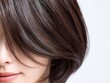 © Arch & Human Studio - 艶やかな茶髪のボブヘアが美しい口角を上げて微笑む若い女性のヘアスタイルのクローズアップ