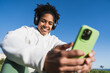 © Westend61 - Smiling woman with headphones taking selfie outdoors on a sunny day