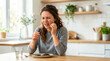 © Xenia - Woman grimacing in pain while eating chocolate in kitchen. Tooth sensitivity and dental ache concept. Person touching cheek with toothache