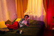 © _KUBE_ - Teen relaxing on bed with music and headphones, enjoying her favorite tracks in sunset-colored room. Comfort and youth. Wide shot