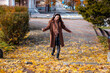 © _KUBE_ - Wide shot of a happy young Caucasian woman in a coat listening to music with headphones and dancing in park. Top view. Concept of happiness and freedom