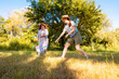 © _KUBE_ - Young girl and mother in sportswear actively playing badminton in city park. Family activity, fun movement and parenting on summer vacation. Bottom view