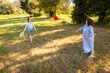 © _KUBE_ - Mother and young daughter playing frisbee on green field in public park. Family time, casual clothing, cheerful mood and natural setting during summer holiday. Wide shot