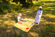 © _KUBE_ - Mother and daughter Caucasian family enjoying a summer park picnic sitting on a blanket playing games and sharing joyful moments outdoors. Top view