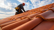 © Tetyana - Experienced roofer installing new red ceramic tiles on a residential house roof, ensuring home construction, maintenance, and repair for property improvement, copy space