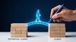 © FAHEEM - Businessman drawing a glowing bridge between wooden blocks labeled 'potential client' and 'client' with a blue pen on a white table against a dark background