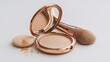 © onepanda - A compact powder case with a mirror, a makeup brush, and a powder puff scattered with loose powder are arranged on a white surface