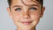© Nataliia_Trushchenko - Young boy with light brown hair and blue eyes smiles directly at the camera, showcasing freckles on his cheeks against a neutral background