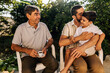 © kleberpicui - Grandfather, adult son and young grandson sitting outdoors and interacting with affection, representing family bonding and multigenerational connection.