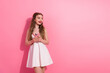 © deagreez - Young woman holding a pink phone while standing against a vibrant pink backdrop with a cheerful expression