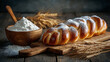 © Алексей Иванченко - A golden braided bread dusted with powdered sugar sits on a wooden board A golden braided bread topped with powdered sugar sits on a wooden cutting board next to a bowl of flour and wheat stalks