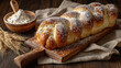 © Алексей Иванченко - A golden braided bread dusted with powdered sugar sits on a wooden board A golden braided bread topped with powdered sugar sits on a wooden cutting board next to a bowl of flour and wheat stalks