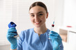 © New Africa - Nurse holding syringe with blood sample and medical tourniquet in clinic, selective focus