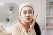 © Pixel-Shot - Beautiful young happy Asian woman with mask on her face in bathroom