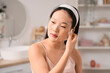 © Pixel-Shot - Beautiful young happy Asian woman taking off facial sheet mask in bathroom
