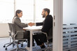 © fizkes - Smiling multiethnic businesspeople handshaking, confirming agreement in office meeting, start partnership, closing business deal. Successful job interview result, corporate teamwork or employment