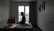 © Teeradej - Mental wellness, depression. A male person sits on bed in dimly lit room, creating contemplative mood