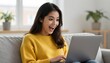 © Monster - Young woman with excited expression looking at laptop screen while sitting on a couch