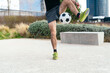 © Koldo_Studio - Male athlete practicing freestyle soccer skills, balancing ball on his leg in a modern city park setting
