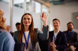 © Drazen - Happy businesswoman raising hand to ask question during conference in board room.