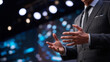 © Ally_art - Businessman gesturing while giving presentation on stage. Speaker in suit delivering speech at professional business conference. Leadership, corporate communication and public speaking event.