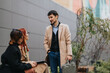 © qunica.com - A man and two colleagues talk together outside an office building during the workday. The group holds a casual business conversation in an urban outdoor workspace.