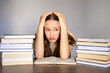 © Ina - Stressed teenage girl studying with books, holding head and feeling overwhelmed. Exam pressure, school stress, education difficulty and mental load concept.