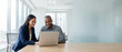 © Bright Stock - Cheerful diverse business professionals using a laptop at a desk in a bright office. Wide banner with right copy space