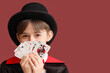 © Pixel-Shot - Little magician with playing cards on brown background, closeup