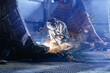 © Parilov - Welder kneeling cutting large excavator bucket inside factory bay, recovery work of industry work