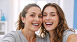 © NeuroCake - Mother and adult daughter taking a selfie and smiling. Happy women bonding and celebrating Mother's Day at home