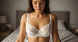 © Baby - Woman wearing white lace bra standing in bedroom interior
