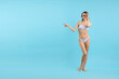 © New Africa - Beautiful woman in stylish swimsuit and sunglasses pointing at something on light blue background. Space for text
