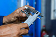 © Jumain - Close-up of mechanic's hands using a vernier caliper to measure the diameter of a metal bolt head during a precision technical inspection in a workshop.