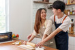 © Crystal - Happy Asian couple preparing dough for homemade bread, sharing a loving moment while cooking in their modern kitchen