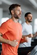 © Andrii Zastrozhnov - Male caucasian adult and male african adult running on gym treadmills two men jogging indoors in modern fitness center during cardio workout and training session