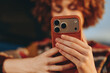 © SHOTPRIME STUDIO - Woman with curly hair wearing a rainbow sweater smiling while holding smartphone, casual lifestyle moment, warm indoor lighting, relaxed and happy expression.
