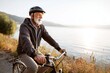 © Anna Lurye - Active senior man riding a classic bicycle along a scenic lakeside path at sunset for healthy lifestyle and retirement wellness concept