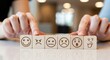 © naima - Fingers touching wooden blocks with icons of various moods for emotional intelligence and mental wellness in a bright commercial setting