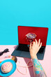 © master1305 - Hand taking cocktail glass from laptop screen with beauty and lifestyle objects on table. Concept of lifestyle service platform, premium product delivery, cross category ecommerce experience.