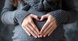 © Prayoga - Pregnant Womans Hands Forming a Heart Shape Over Her Belly.