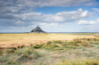 © robertharding - Mont Saint Michel rises from tidal flats under a cloudy sky in Normandy, France, capturing the essence of the historic landscape