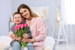© New Africa - Little boy greeting his mom with flowers at home. Space for text